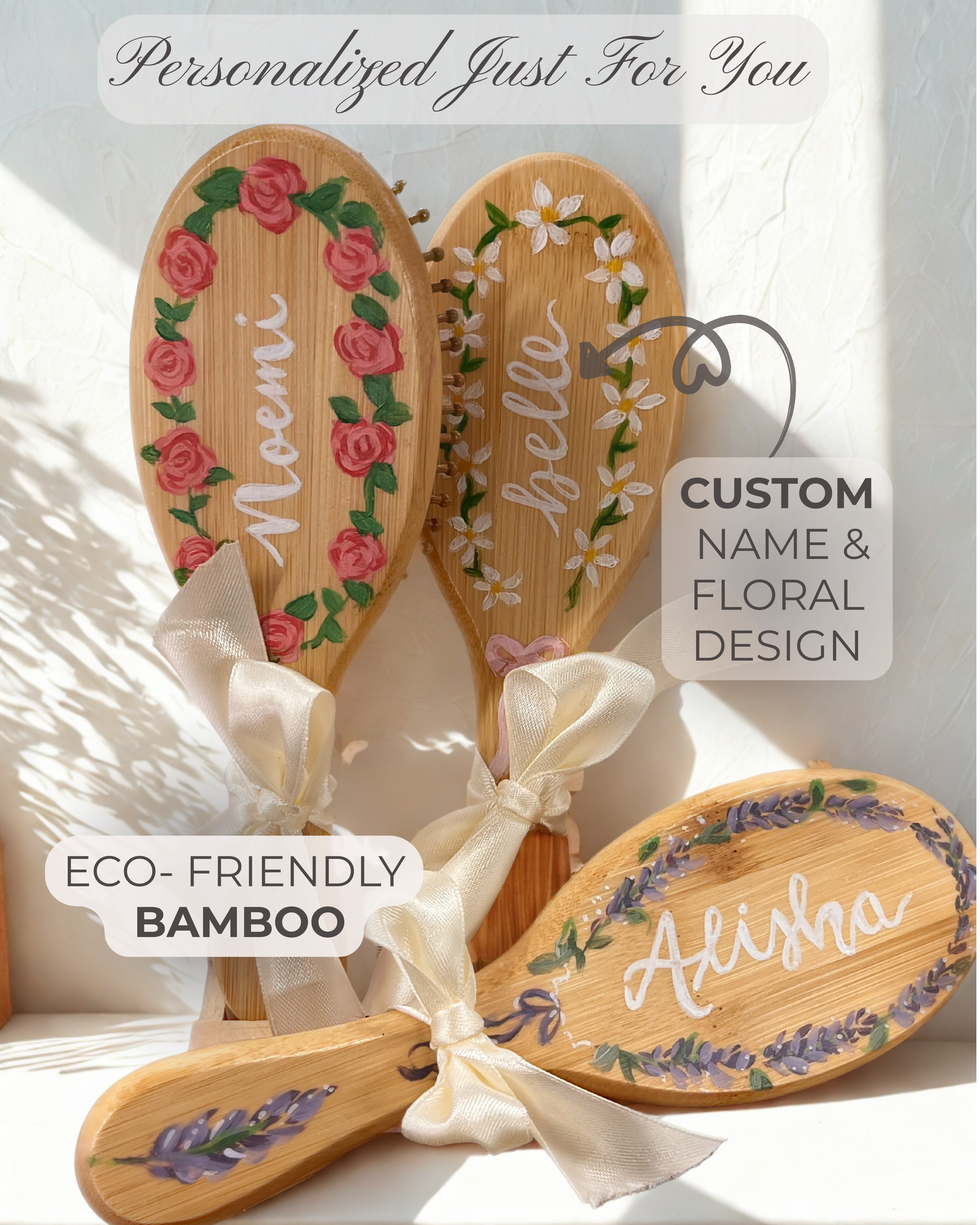 Three wooden hairbrushes with floral designs and names on a white background